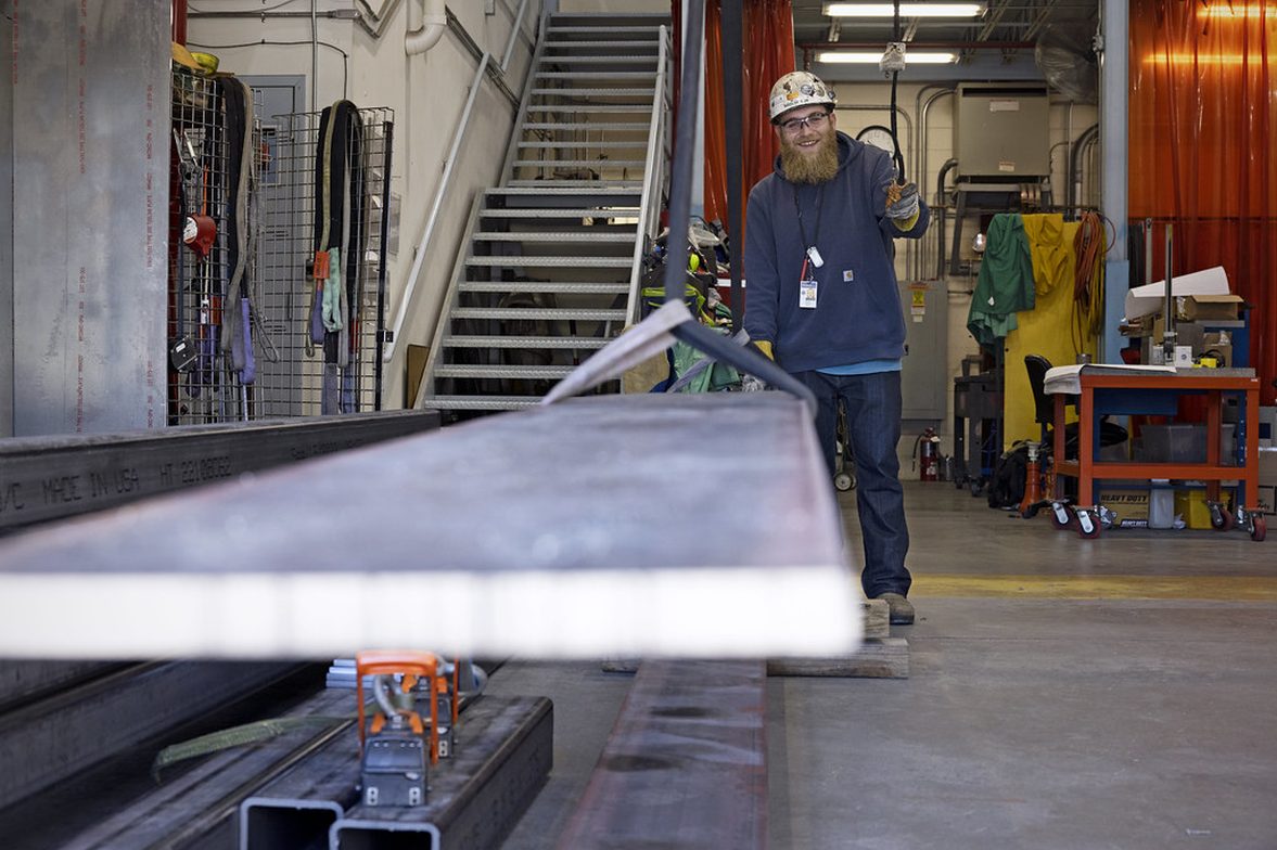 Metal fabrication workshop with a technician handling steel section